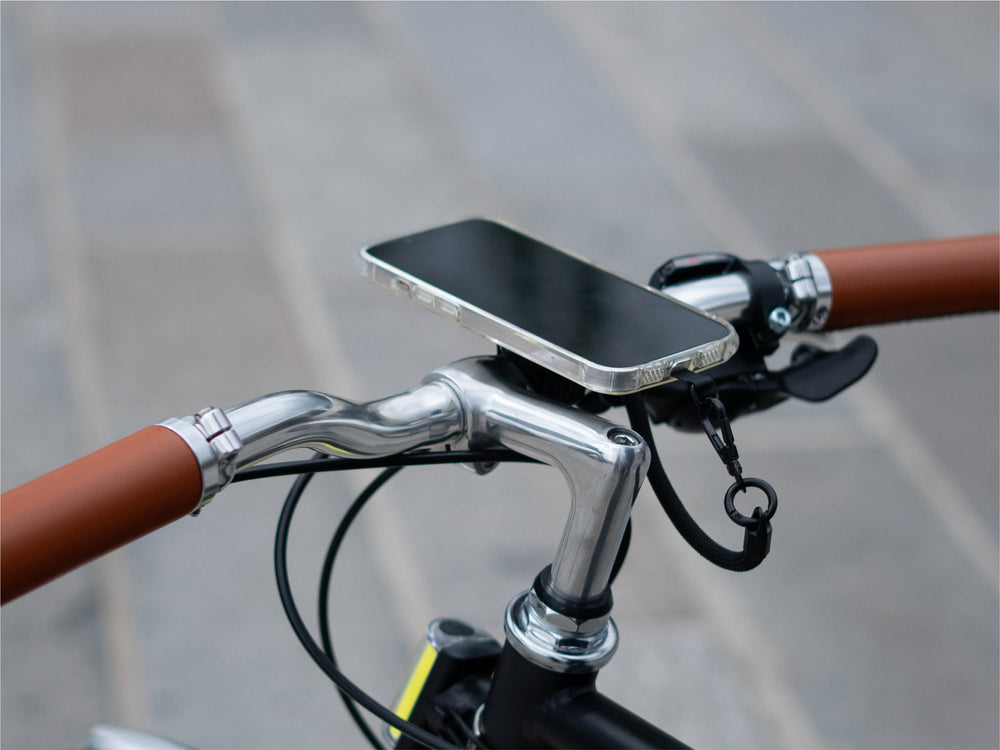 El smartphone se fija magnéticamente al soporte del manillar, lo que demuestra una configuración minimalista. El cordón proporciona mayor seguridad.